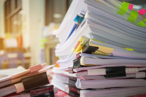 Paper stack Pile of unfinished documents on office desk related to business functions.