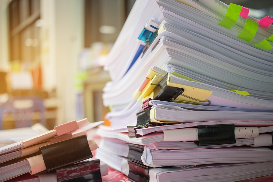 Paper stack Pile of unfinished documents on office desk related to business functions.
